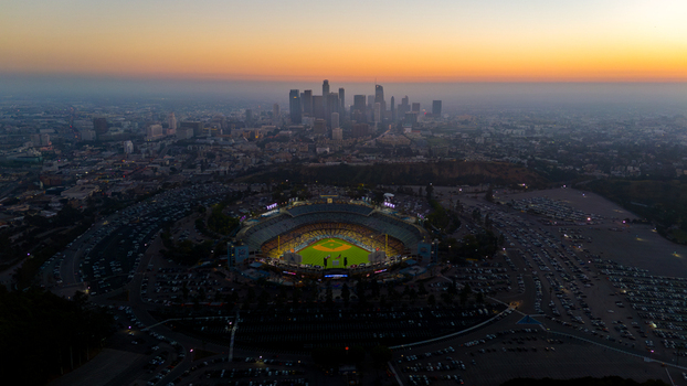 Aerial view of Dodger Stadium s bright lights shining amidst a sea of parked cars under a smoky sky Los Angeles California United States. Aerial view of Dodger Stadium s bright lights shining amidst a sea of parked cars under a smoky sky Los Angeles California United States.