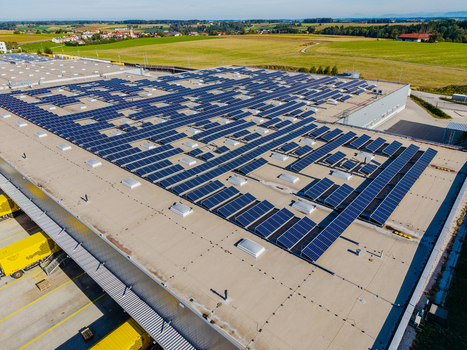 Aerial view of Logistikzentrum Allhaming featuring a large rooftop covered in solar panels with yellow logistics trucks parked at the loading bays in Allhaming Oberosterreich Austria. Aerial view of Logistikzentrum Allhaming featuring a large rooftop covered in solar panels with yellow logistics trucks parked at the loading bays in Allhaming Oberosterreich Austria.