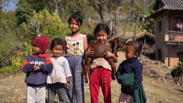 View of children holding a small goat in a rural village Nepal.