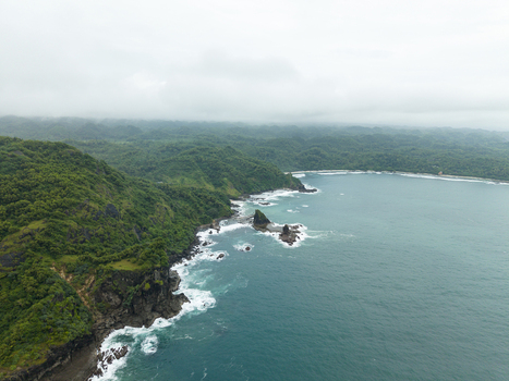 Aerial view of where the rugged verdant cliffs meet the turquoise sea at Pengilon Hill Gunungkidul Regency Daerah Istimewa Yogyakarta Indonesia. Aerial view of where the rugged verdant cliffs meet the turquoise sea at Pengilon Hill Gunungkidul Regency Daerah Istimewa Yogyakarta Indonesia.