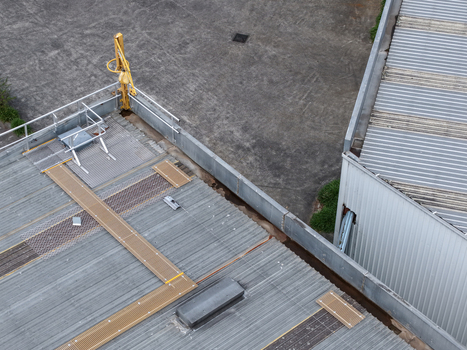 Aerial view of an industrial facility rooftop with corrugated metal surfaces safety walkways and mechanical equipment in Melbourne VIC Australia.
