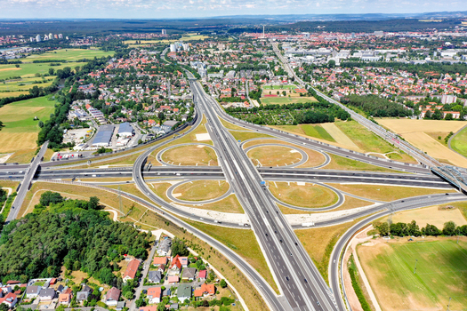 Aerial view of the A73 highway interchange with its cloverleaf junction surrounded by residential areas and green fields in Nurnberg Bayern Germany. Aerial view of the A73 highway interchange with its cloverleaf junction surrounded by residential areas and green fields in Nurnberg Bayern Germany.