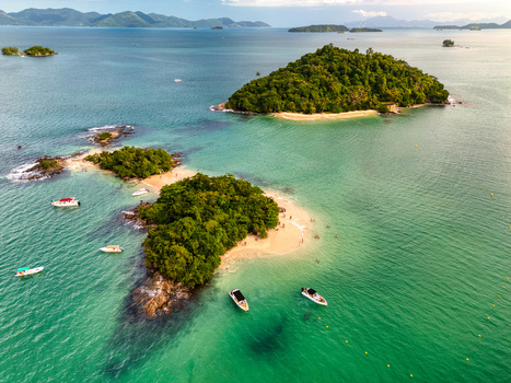 Aerial view of Ilha Cataguas featuring lush green islands with sandy beaches surrounded by turquoise water and anchored boats in Rio de Janeiro Brazil. Aerial view of Ilha Cataguas featuring lush green islands with sandy beaches surrounded by turquoise water and anchored boats in Rio de Janeiro Brazil.
