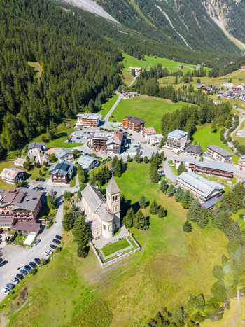Aerial view of the village of Sulden with its historic church surrounded by green alpine meadows dense pine forests and mountain slopes in Sulden Trentino Alto Adige Italy. Aerial view of the village of Sulden with its historic church surrounded by green alpine meadows dense pine forests and mountain slopes in Sulden Trentino Alto Adige Italy.