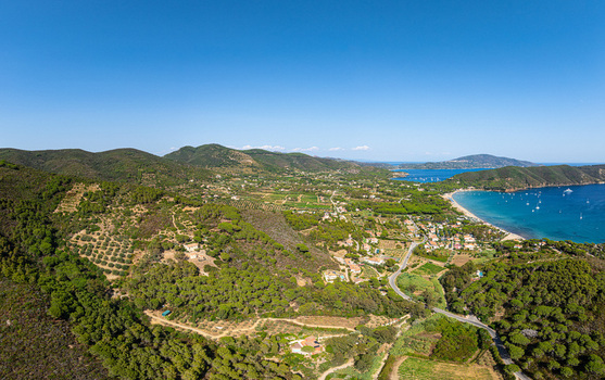 Aerial view of Lacona Beach surrounded by lush green hills Mediterranean vegetation and the blue sea in Lacona Tuscany Italy.