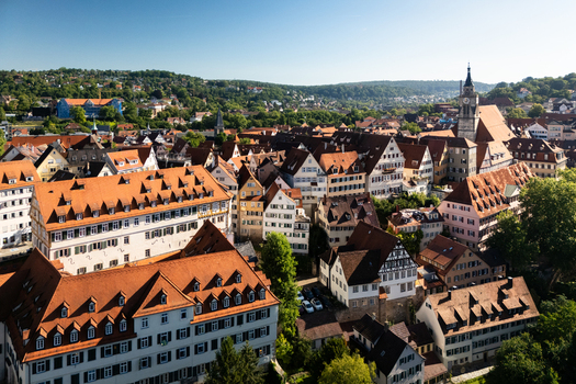 Aerial view of the historic old town with its traditional red tiled rooftops half timbered buildings and the Stiftskirche church tower under a clear blue sky in Tubingen Baden Wurttemberg Germany. Aerial view of the historic old town with its traditional red tiled rooftops half timbered buildings and the Stiftskirche church tower under a clear blue sky in Tubingen Baden Wurttemberg Germany.