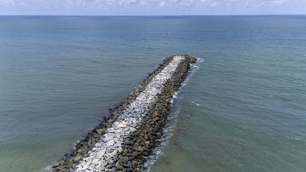 Aerial view of a stone breakwater jetty extending into the turquoise ocean waters under a clear horizon Lekki Lagos Nigeria. Aerial view of a stone breakwater jetty extending into the turquoise ocean waters under a clear horizon Lekki Lagos Nigeria.