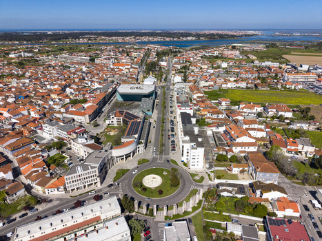 Aerial view of the vibrant roundabout and a long straight road cutting through red roofed buildings towards the distant lagoon Aveiro Portugal. Aerial view of the vibrant roundabout and a long straight road cutting through red roofed buildings towards the distant lagoon Aveiro Portugal.