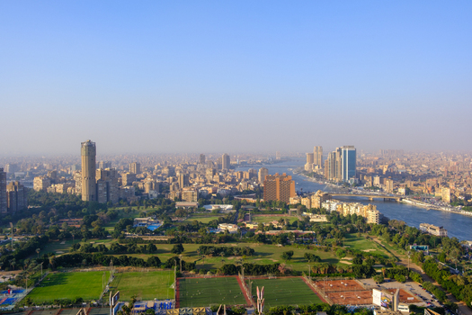 Aerial view of the sprawling cityscape alongside the Nile River with lush green parks contrasting against the urban skyline Cairo Egypt. Aerial view of the sprawling cityscape alongside the Nile River with lush green parks contrasting against the urban skyline Cairo Egypt.