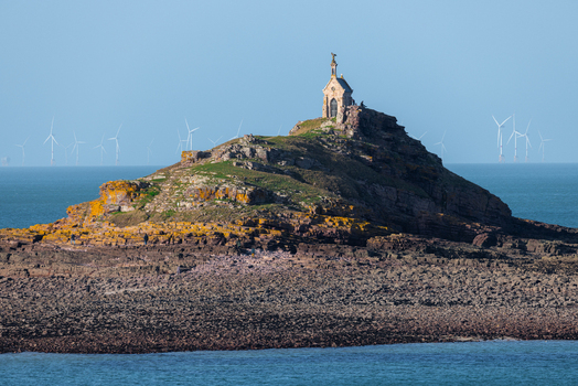 Aerial view of the Saint Michel chapel on a rocky islet with offshore wind turbines on the horizon in Plurien Brittany France. Aerial view of the Saint Michel chapel on a rocky islet with offshore wind turbines on the horizon in Plurien Brittany France.