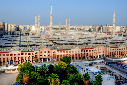 View of Al Masjid e Nabawi with its iconic minarets and expansive courtyard umbrellas under a clear sky in Madinah Al Madinah Province Saudi Arabia. View of Al Masjid e Nabawi with its iconic minarets and expansive courtyard umbrellas under a clear sky in Madinah Al Madinah Province Saudi Arabia.