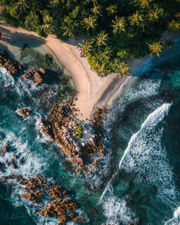 Aerial view of Secret Beach Mirissa with turquoise waves crashing against rocky shores and lush palm trees along the sandy coastline in Mirissa Southern Province Sri Lanka. Aerial view of Secret Beach Mirissa with turquoise waves crashing against rocky shores and lush palm trees along the sandy coastline in Mirissa Southern Province Sri Lanka.