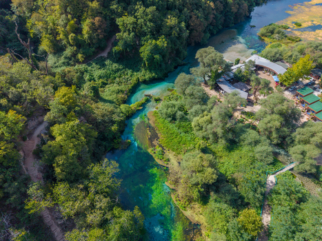 Aerial view of The Blue Eye a natural spring with vibrant turquoise water surrounded by lush green trees and forest vegetation in Saranda Qarku i Vlores Albania. Aerial view of The Blue Eye a natural spring with vibrant turquoise water surrounded by lush green trees and forest vegetation in Saranda Qarku i Vlores Albania.