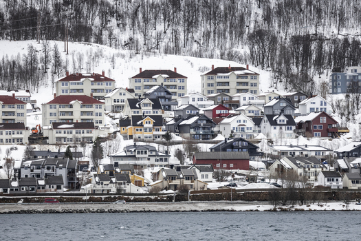 View of colorful houses and apartment buildings on a snow covered hillside overlooking the water in Tromso Troms Norway. View of colorful houses and apartment buildings on a snow covered hillside overlooking the water in Tromso Troms Norway.