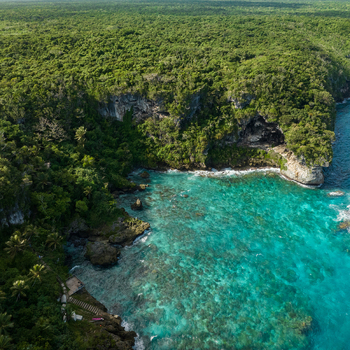 Aerial view of turquoise waters meet lush green cliffs contrasting with the dark shadows of hidden caves along the coast Joking Lifou New Caledonia. Aerial view of turquoise waters meet lush green cliffs contrasting with the dark shadows of hidden caves along the coast Joking Lifou New Caledonia.