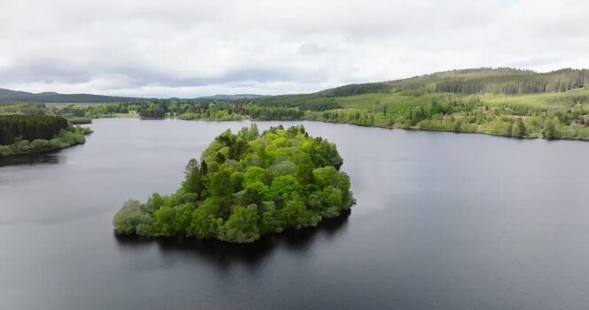 Aerial view of a small forested island in a calm lake United Kingdom. Aerial view of a small forested island in a calm lake United Kingdom.