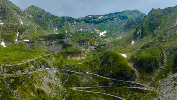 Aerial view of the winding Transfagarasan mountain road cutting through the lush green slopes of the Carpathian Mountains in Curtea de Arges Judetul Arges Romania.