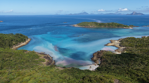 Aerial view of Chance Bay with its turquoise waters white sandy beach and surrounding lush green vegetation in the Whitsundays Queensland Australia. Aerial view of Chance Bay with its turquoise waters white sandy beach and surrounding lush green vegetation in the Whitsundays Queensland Australia.