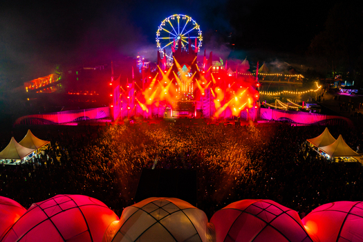 Herzogenaurach Germany 22 July 2022 Aerial view of the Open Beatz Festival featuring a massive stage with red lights a Ferris wheel and a large crowd at night. Herzogenaurach Germany 22 July 2022 Aerial view of the Open Beatz Festival featuring a massive stage with red lights a Ferris wheel and a large crowd at night.