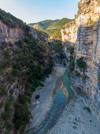 Aerial view of Osumi Canyon featuring steep limestone cliffs a winding river and lush vegetation in Dhores Berat County Albania.