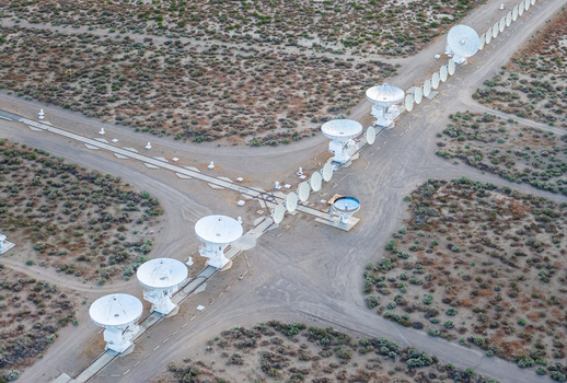 Aerial view of the radio telescope array with large white satellite dishes arranged on tracks in the arid desert landscape of Inyo County California United States.