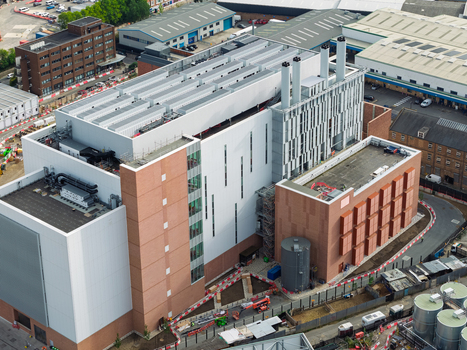 Aerial view of a modern data center facility featuring brick and white panel facades industrial ventilation systems and rooftop equipment in an urban setting United Kingdom. Aerial view of a modern data center facility featuring brick and white panel facades industrial ventilation systems and rooftop equipment in an urban setting United Kingdom.