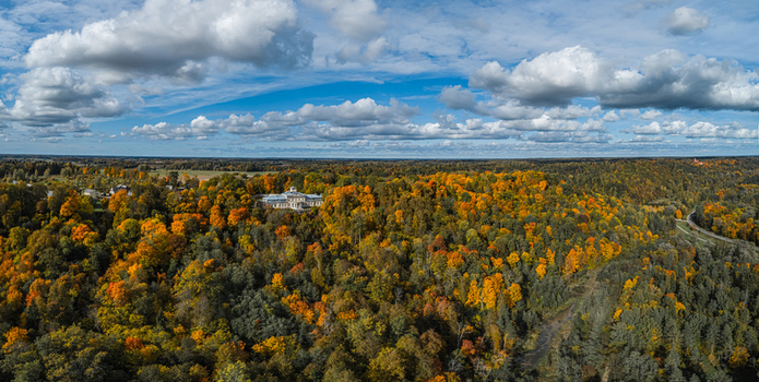 Aerial view of Sigulda New Castle nestled within a vibrant autumn forest with colorful foliage under a blue sky with scattered clouds in Sigulda Sigulda Municipality Latvia. Aerial view of Sigulda New Castle nestled within a vibrant autumn forest with colorful foliage under a blue sky with scattered clouds in Sigulda Sigulda Municipality Latvia.