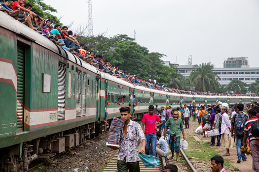 Dhaka Bangladesh 14 June 2018 View of Airport Railway Station with a crowded passenger train where people are sitting on the roof and walking along the tracks. Dhaka Bangladesh 14 June 2018 View of Airport Railway Station with a crowded passenger train where people are sitting on the roof and walking along the tracks.