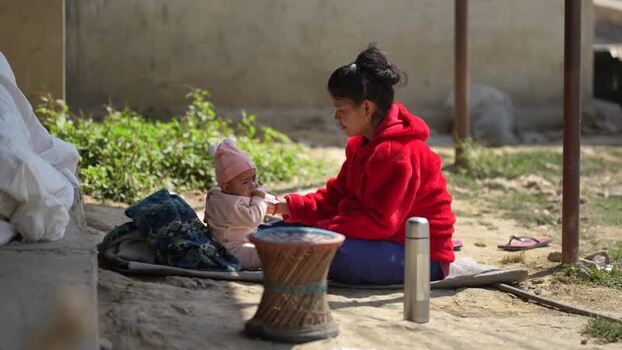 View of a woman sitting outdoors with her baby and a thermos Nepal. View of a woman sitting outdoors with her baby and a thermos Nepal.