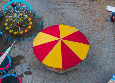 Aerial view of a colorful carousel with red and yellow stripes and a nearby swing ride at a fairground in Vilnius Vilnius County Lithuania. Aerial view of a colorful carousel with red and yellow stripes and a nearby swing ride at a fairground in Vilnius Vilnius County Lithuania.
