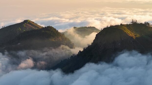 Aerial view of Dieng Plateau peaks above clouds in Indonesia.
