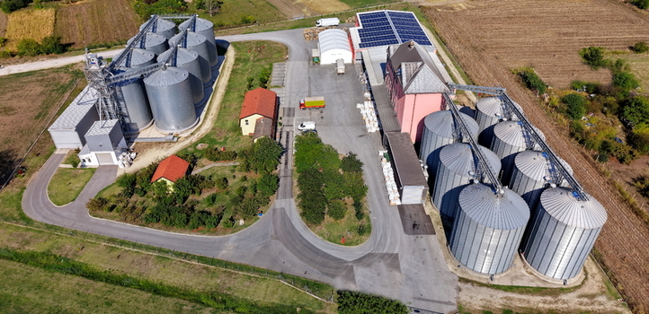 Aerial view of the storage silo Bavaniste facility featuring multiple metal grain silos industrial buildings with solar panels and paved access roads in Bavaniste Vojvodina Serbia.