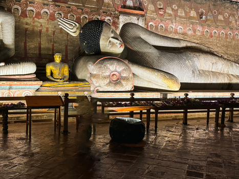 Sri Lanka 20 April 2024 View of the ancient reclining Buddha statue inside the Dambulla Cave Temple featuring intricate wall paintings and warm lighting.