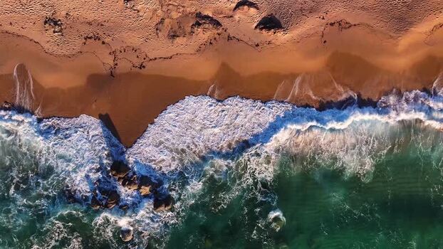 Aerial view of waves crashing on the sandy beach of Costa Paradiso Italy. Aerial view of waves crashing on the sandy beach of Costa Paradiso Italy.