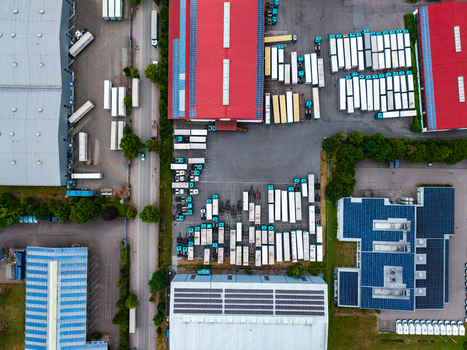 Aerial view of Neuenstein Techno Zone featuring industrial warehouses with red roofs rows of parked semi trucks and solar panels in Neuenstein Baden Wurttemberg Germany. Aerial view of Neuenstein Techno Zone featuring industrial warehouses with red roofs rows of parked semi trucks and solar panels in Neuenstein Baden Wurttemberg Germany.
