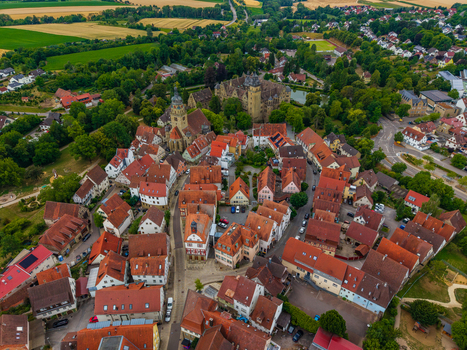 Aerial view of Schloss Neuenstein and the historic town center with red tiled rooftops lush greenery and surrounding fields in Neuenstein Baden Wurttemberg Germany. Aerial view of Schloss Neuenstein and the historic town center with red tiled rooftops lush greenery and surrounding fields in Neuenstein Baden Wurttemberg Germany.