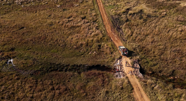 Aerial view of workers preparing firebreaks in the African grassland with a vehicle parked on a dirt road near a small stream in Modimolle Limpopo South Africa. Aerial view of workers preparing firebreaks in the African grassland with a vehicle parked on a dirt road near a small stream in Modimolle Limpopo South Africa.