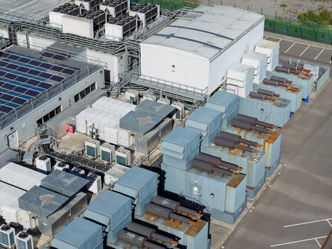Aerial view of a data center rooftop featuring large industrial cooling units solar panels and surrounding infrastructure in the United Kingdom.