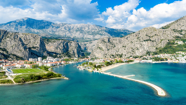 Aerial view of the historic town at the mouth of the Cetina river surrounded by dramatic limestone cliffs and the turquoise Adriatic Sea in Omis Split Dalmatia County Croatia. Aerial view of the historic town at the mouth of the Cetina river surrounded by dramatic limestone cliffs and the turquoise Adriatic Sea in Omis Split Dalmatia County Croatia.
