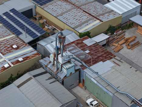 Melbourne VIC Australia 25 September 2026 Aerial view of an industrial factory site with corrugated metal roofs a dust extraction system timber stacks and solar panels.