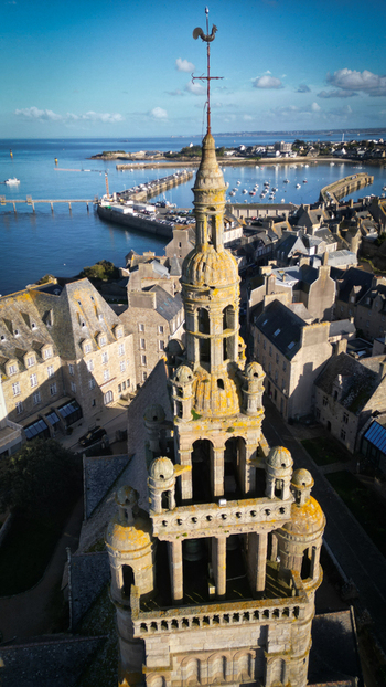 Aerial view of weathered stone tower rising towards a brilliant blue sky overlooking the harbor dotted with boats Roscoff Bretagne France. Aerial view of weathered stone tower rising towards a brilliant blue sky overlooking the harbor dotted with boats Roscoff Bretagne France.