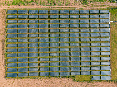 Aerial view of a large solar farm with rows of photovoltaic panels arranged in a grid pattern on open land in Ogun State Nigeria.