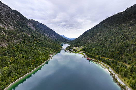 Aerial view of the serene Plansee lake reflecting the cloudy sky embraced by lush green forests nestled between towering mountains Plansee Tyrol Austria. Aerial view of the serene Plansee lake reflecting the cloudy sky embraced by lush green forests nestled between towering mountains Plansee Tyrol Austria.