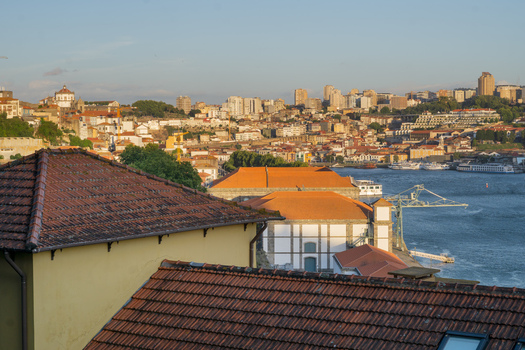 View of warm terracotta roofs cascading towards the shimmering Douro River framed by the modern skyline in Porto Porto Portugal. View of warm terracotta roofs cascading towards the shimmering Douro River framed by the modern skyline in Porto Porto Portugal.