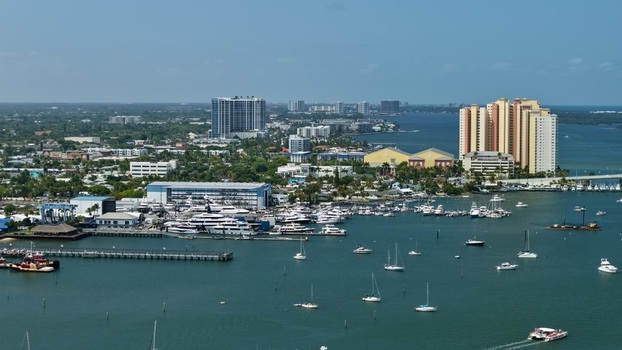 Aerial view of the marina and urban skyline with luxury yachts and sailboats docked in the blue waters of Palm Beach County Florida United States.