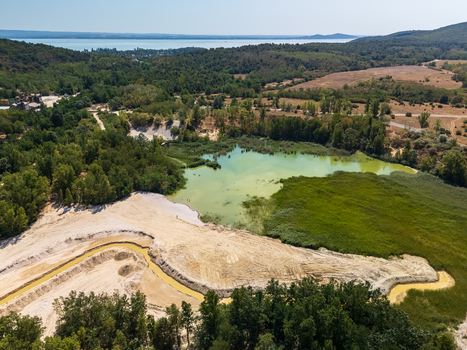 Aerial view of Burnout Lake near Salfold in Hungary s Balaton Uplands a former quarry lake with forested shoreline reeds and summer greenery in a protected rural landscape.