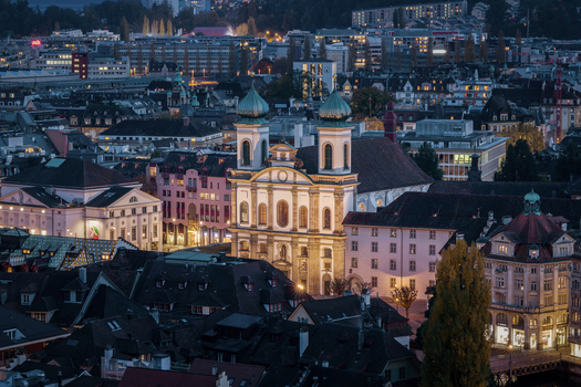 View of the illuminated Jesuit Church and historic rooftops at dusk in the old town of Lucerne Lucerne Switzerland. View of the illuminated Jesuit Church and historic rooftops at dusk in the old town of Lucerne Lucerne Switzerland.