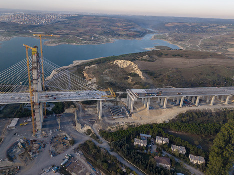 Aerial view of a large cable stayed bridge under construction with tall cranes and concrete pillars spanning across a reservoir in Istanbul Istanbul Turkiye.