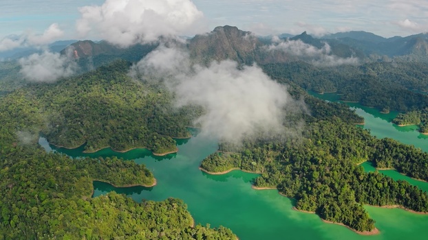 Aerial view of Khao Sok National Park featuring lush rainforest limestone mountains and the turquoise waters of Cheow Lan Lake in Surat Thani Surat Thani Thailand. Aerial view of Khao Sok National Park featuring lush rainforest limestone mountains and the turquoise waters of Cheow Lan Lake in Surat Thani Surat Thani Thailand.