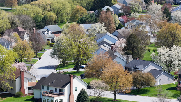 Aerial view of a quiet suburban residential neighborhood with houses lush green lawns and trees in spring bloom in East Petersburg Pennsylvania United States.